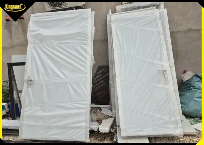 Hai cánh của bộ cửa panel 2 cánh màu trắng còn nguyên màng nilon bảo vệ trước khi lắp đặt.