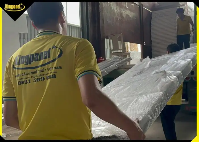 Nhân viên đang vận chuyển các tấm panel cách nhiệt bọc nilon để chuẩn bị thi công lắp đặt cửa panel 2 cánh.